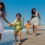 Cheerful family playing and running on a sunny beach, enjoying a vacation day together.
